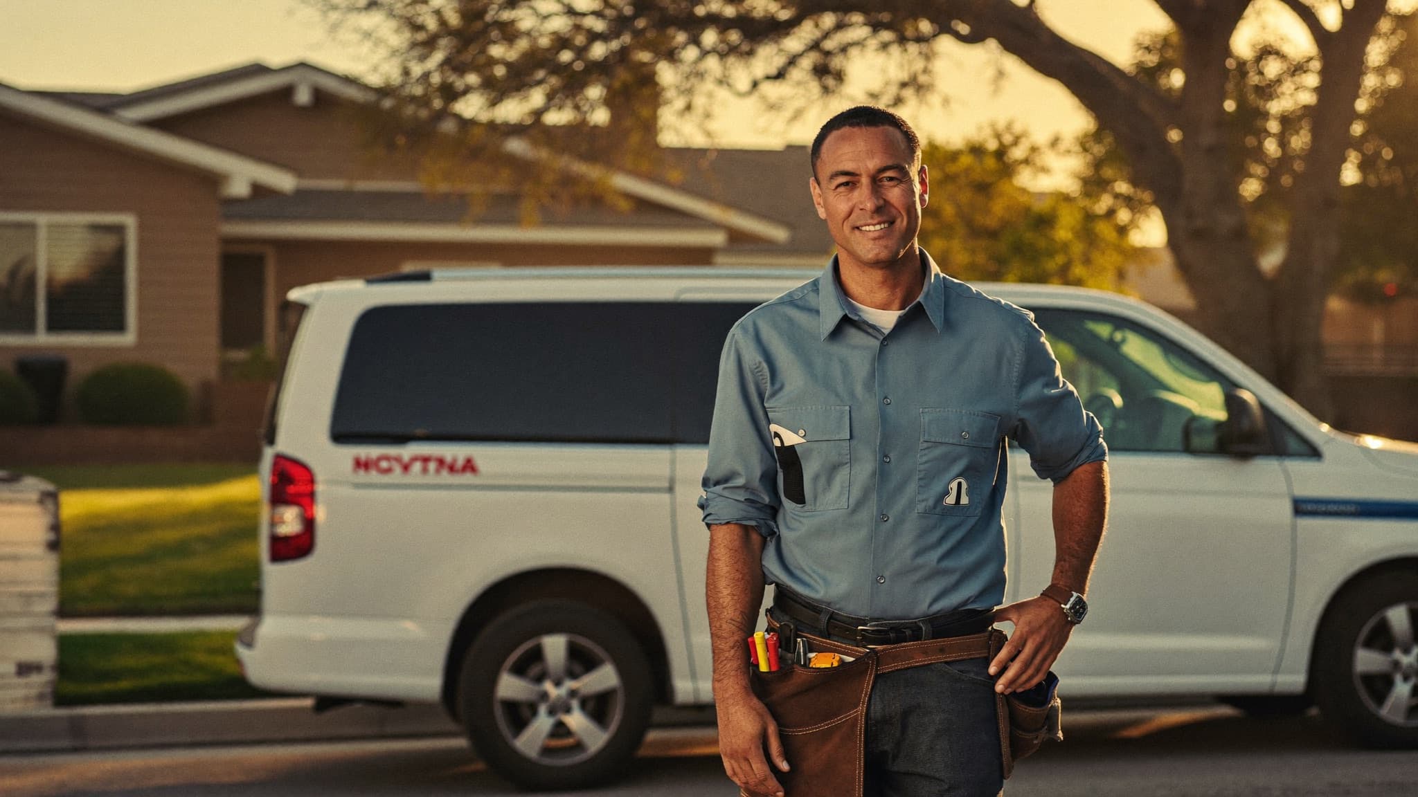 A local home-service business owner standing in front of his work van at golden hour